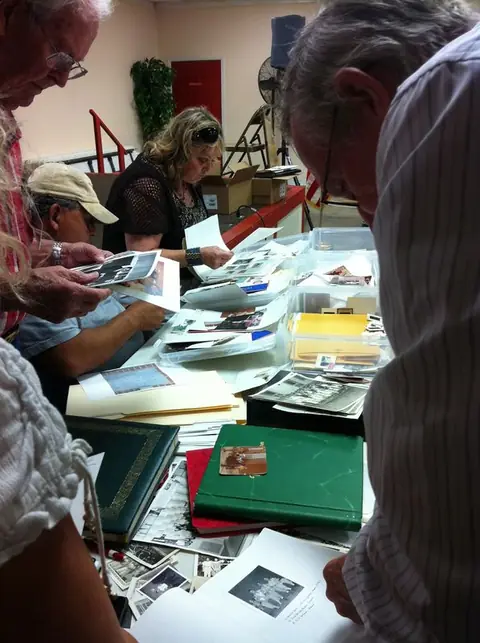 People looking through albums of old photographs spread across a table